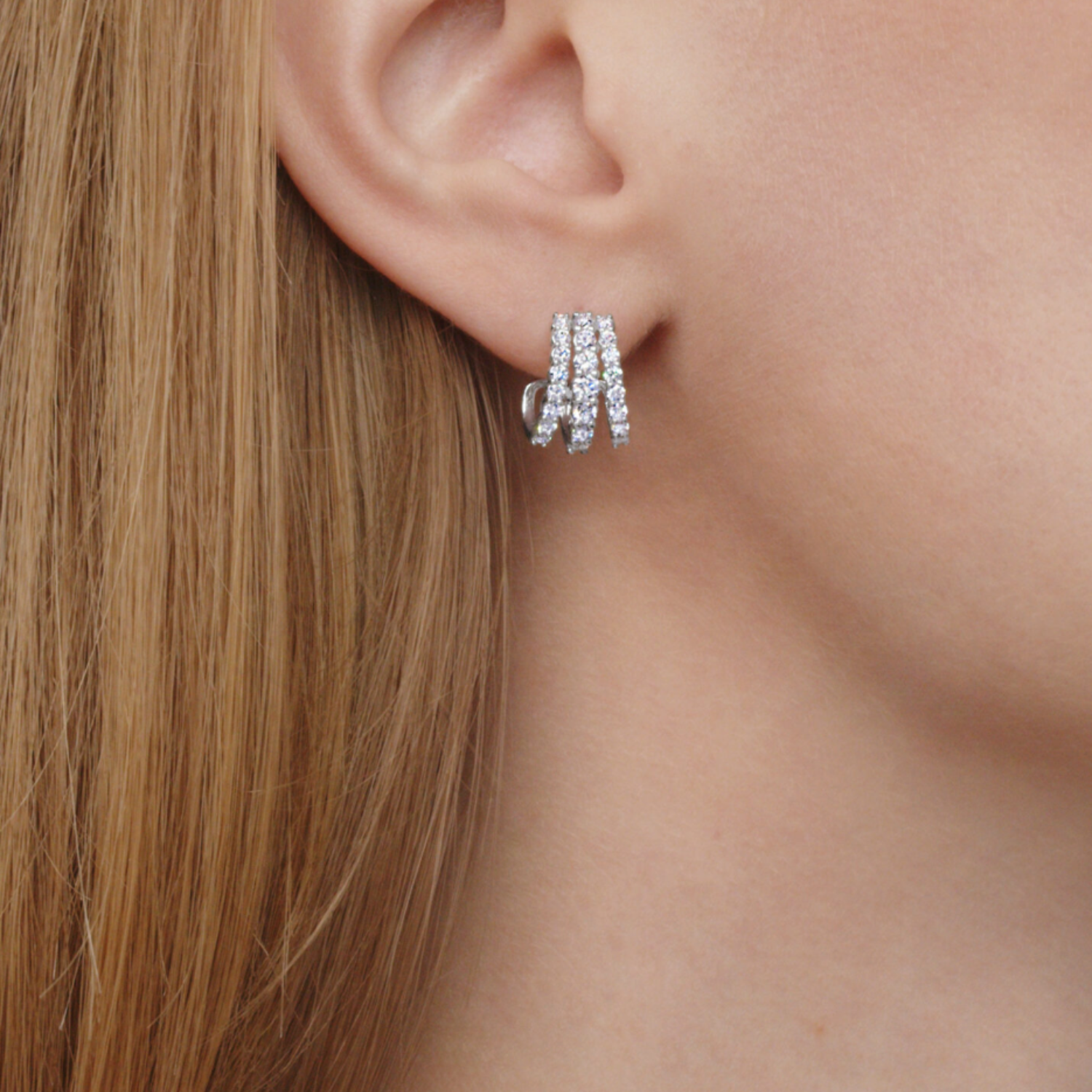 Close-up of a person wearing silver hoop earrings with a blurred background