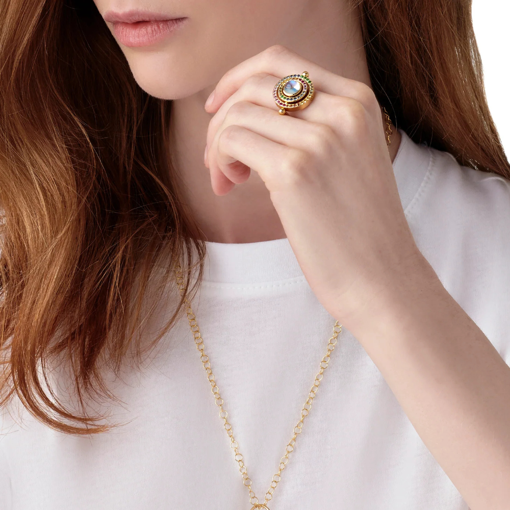 Close-up of a person wearing a gold ring and necklace on a white background