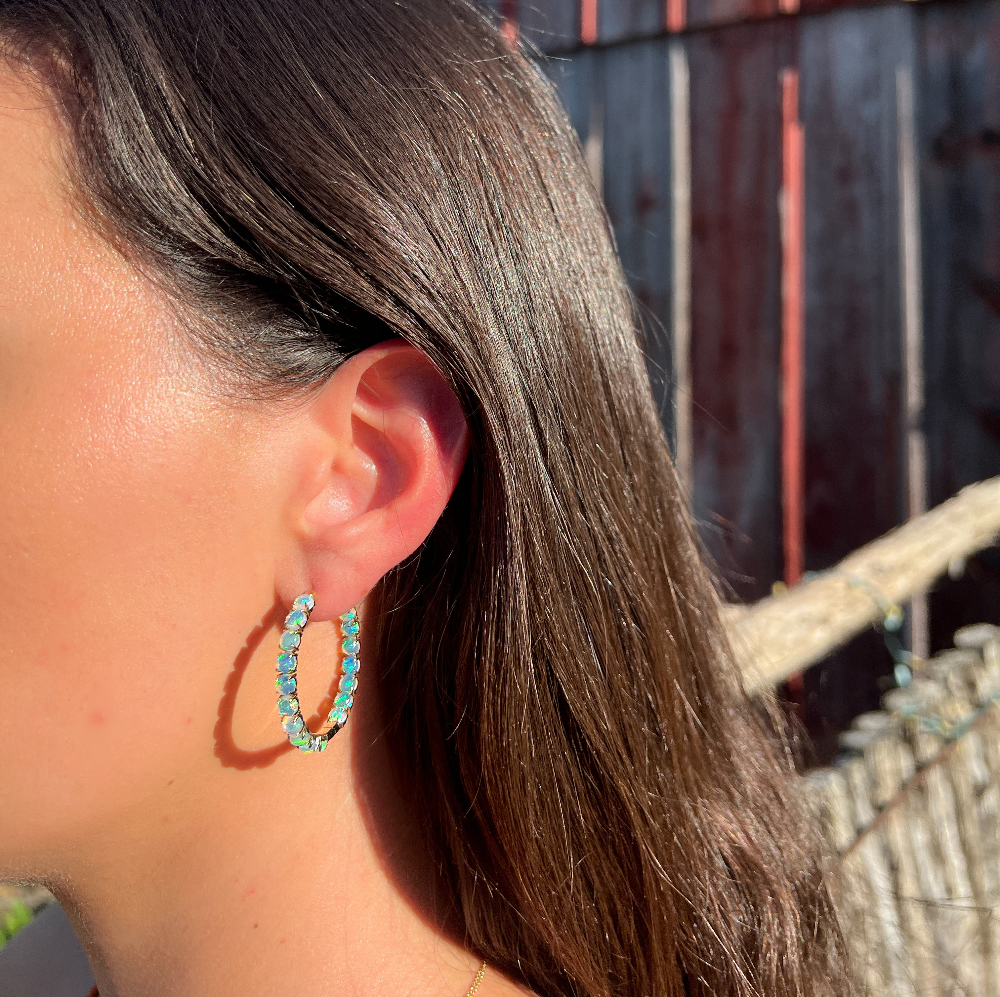 Close-up of a person wearing turquoise hoop earrings with a blurred background