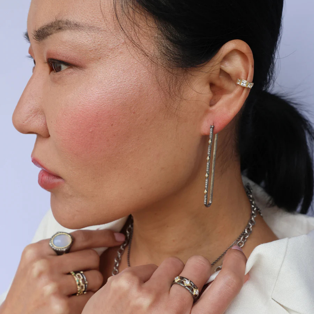Close-up of a woman wearing earrings and rings with a light purple background