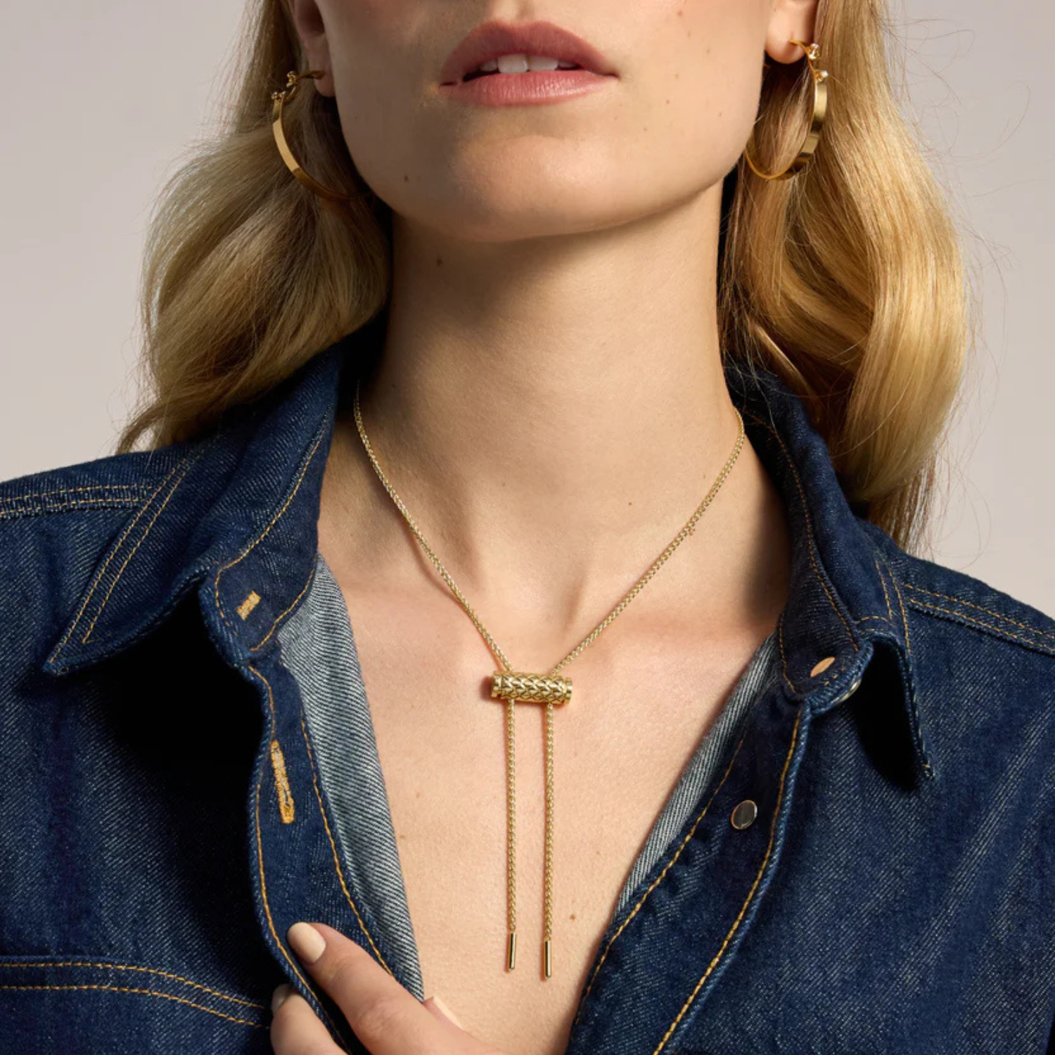 Woman wearing a gold necklace with a minimalistic design, close-up shot.