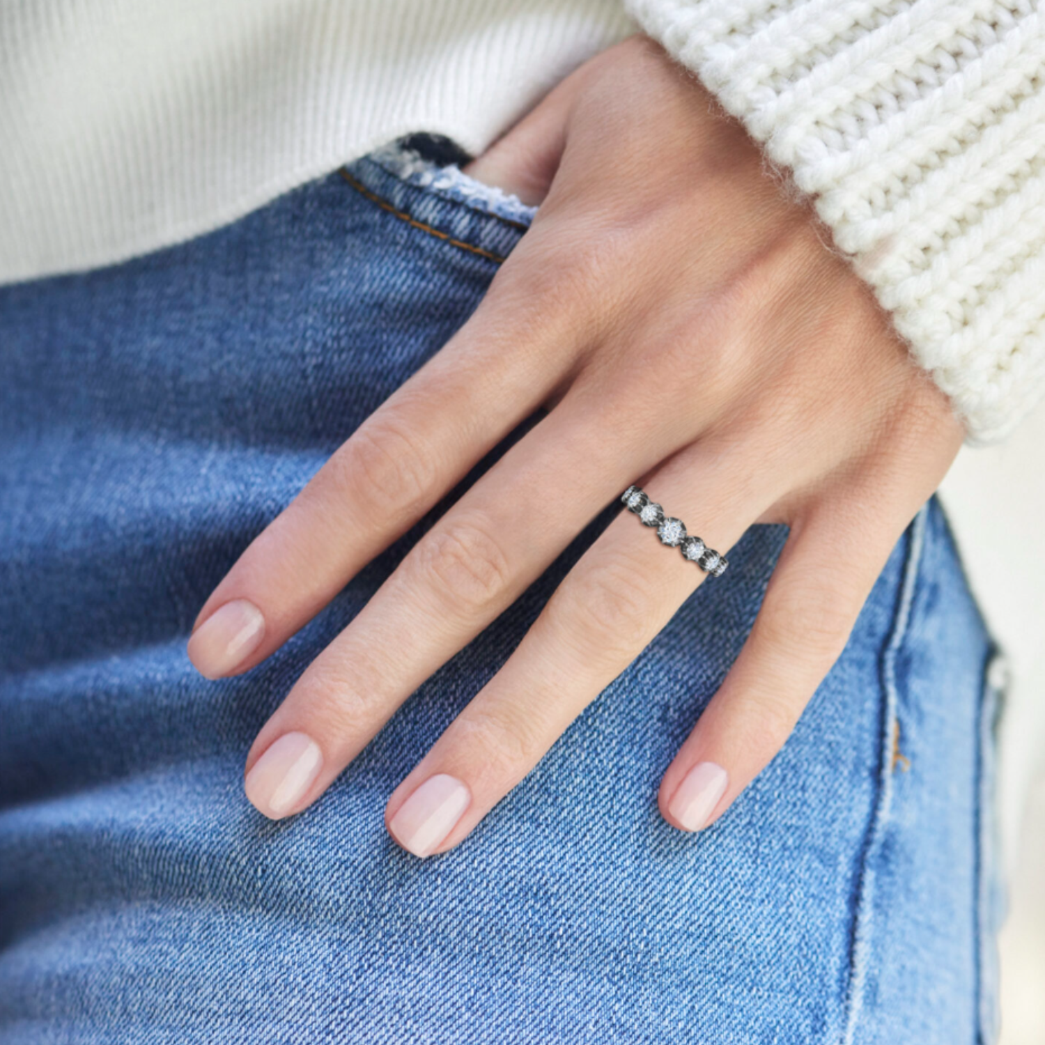 Hand wearing a diamond ring on a denim background