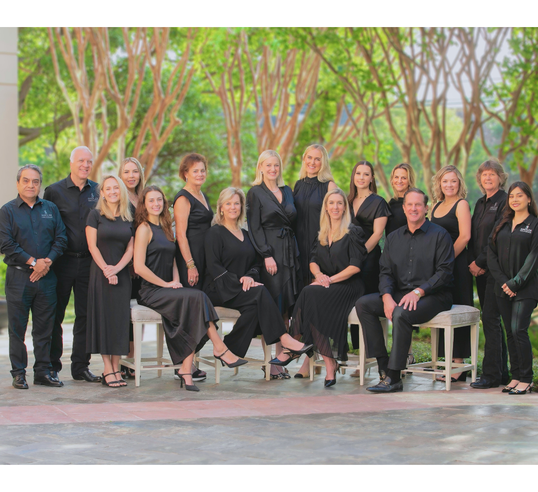 Group of people in formal attire posing outdoors with trees in the background